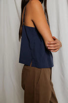 Person wearing a navy blue top and brown pants against a white background