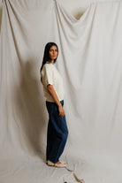 Woman standing against a plain white curtain