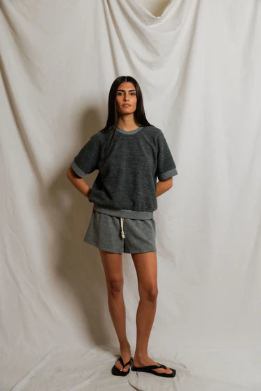 Person wearing a gray outfit standing against a plain white background