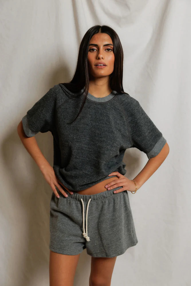 Woman wearing a gray oversized t-shirt and shorts set against a plain background