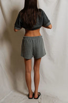 Person wearing a gray crop top and shorts set against a plain background