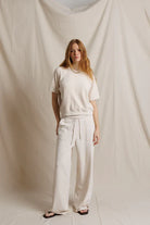 Woman wearing a white outfit standing against a plain background