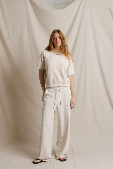 Woman wearing a white outfit standing against a plain background