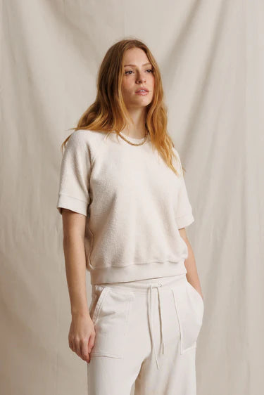 Woman wearing a white outfit against a beige background