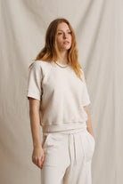 Woman wearing a white outfit against a beige background