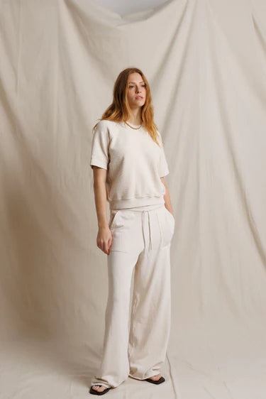 Woman wearing a white outfit standing against a plain white background