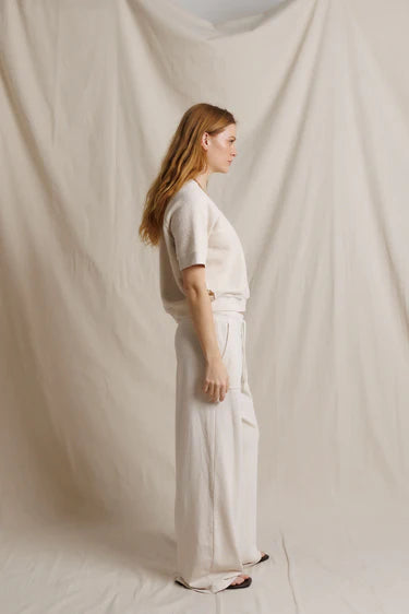 Person wearing a white outfit standing against a plain white background
