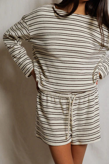 Person wearing a striped long-sleeve top and shorts set against a plain background