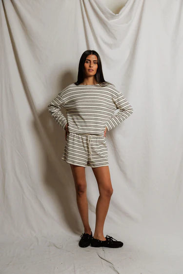 Woman wearing a striped outfit standing against a plain background