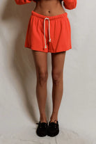 Person wearing bright orange shorts with a white background
