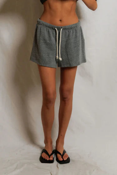 Person wearing gray shorts with a white background
