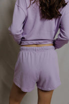 Person wearing a matching lavender long-sleeve top and shorts set against a plain background