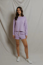 Woman wearing a purple outfit standing against a plain background