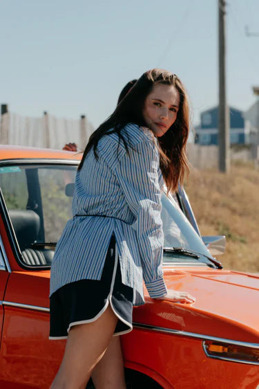 Woman leaning against an orange car with a scenic background