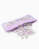 Set of wooden tiles with colorful designs in a purple storage bag on a white background