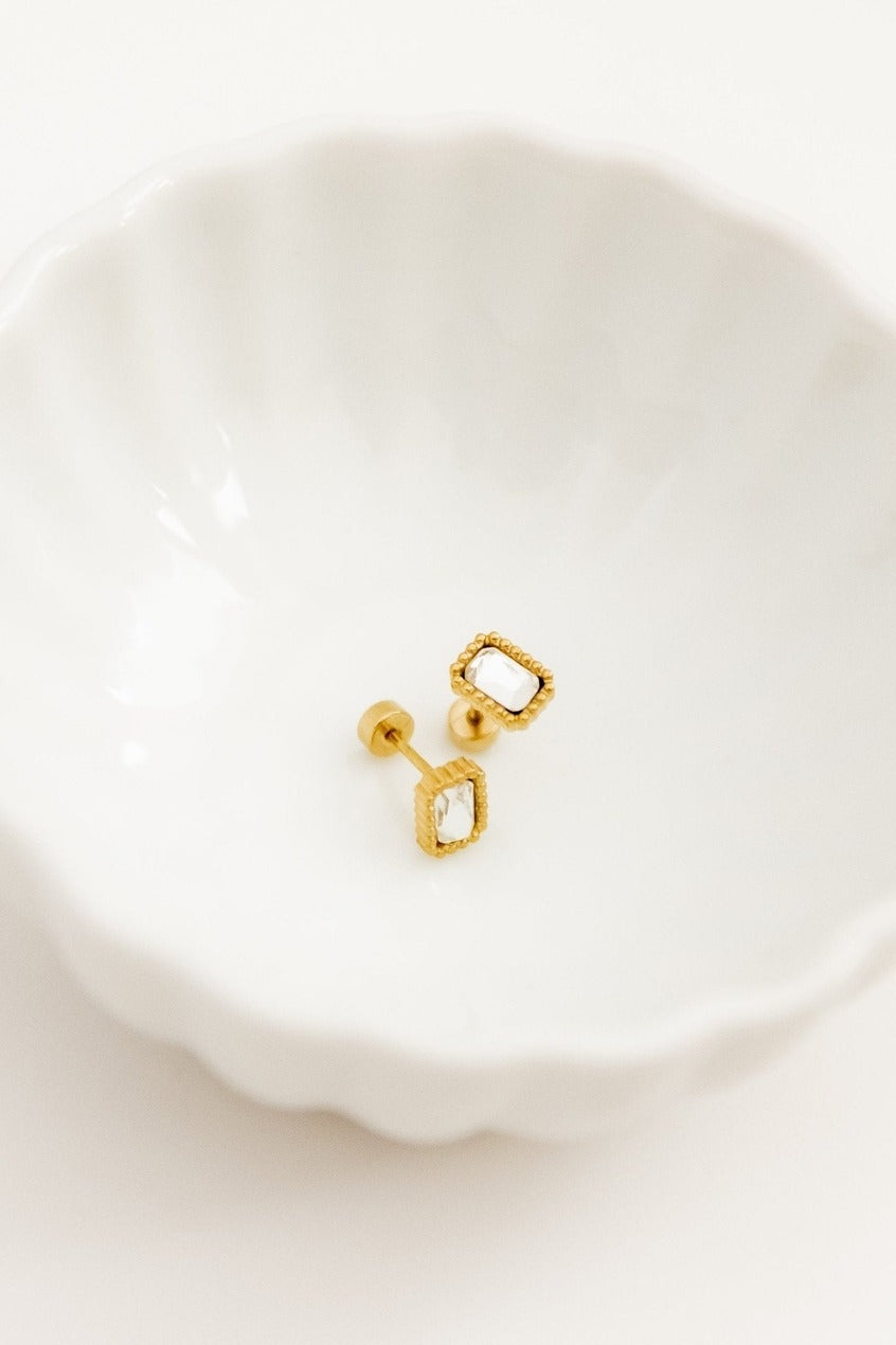 Gold earrings on a white dish with a white background