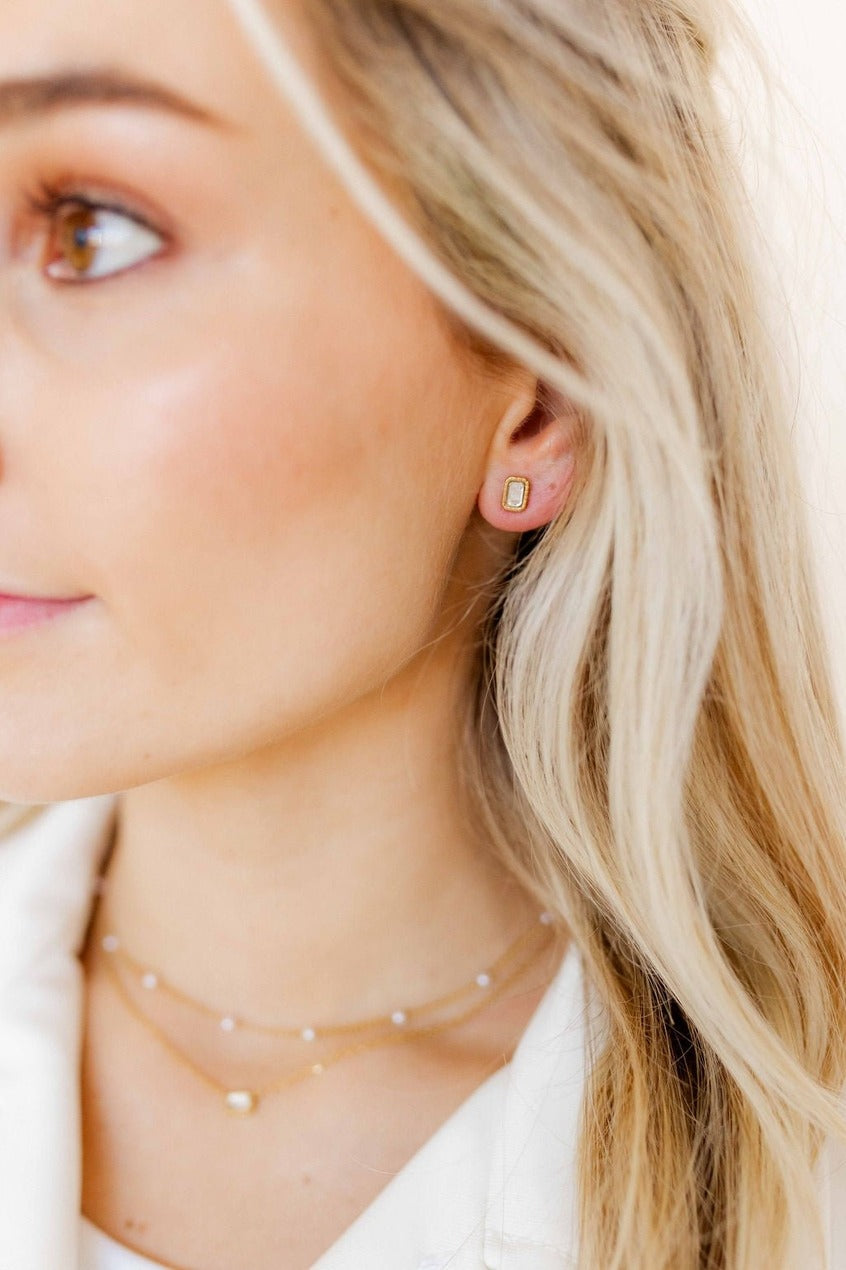 Close-up of a woman wearing gold earrings and necklaces with a blurred background