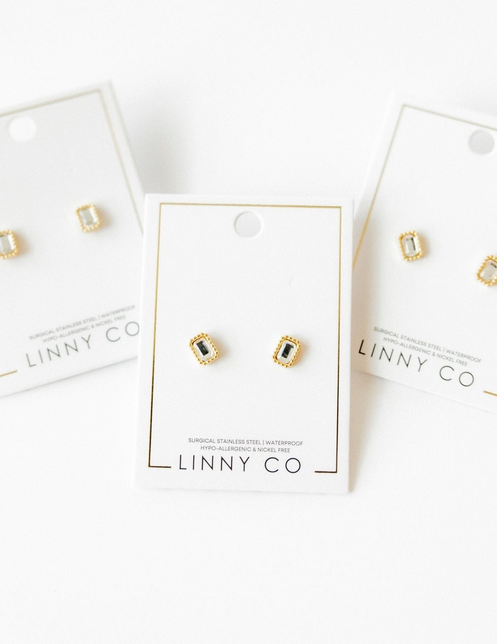 Gold and black stud earrings on LINNY CO branded cards against a white background