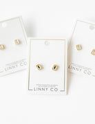 Gold and black stud earrings on LINNY CO branded cards against a white background