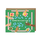 Greeting card with illustration of hands playing a game, text 'Wishing you a lucky year', on a green background.