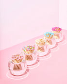 Clear glass holders with colorful matches on a pink background