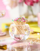 Clear glass container filled with colorful matchsticks on a blurred background