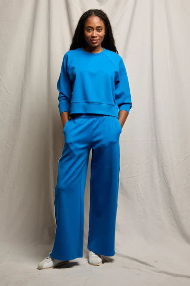 Woman wearing a blue outfit standing against a plain background