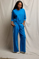 Person wearing a blue tracksuit standing against a plain background