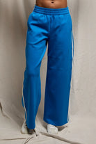 Blue track pants with white stripes on a beige background