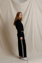 Person wearing a black outfit with white stripes on a beige background