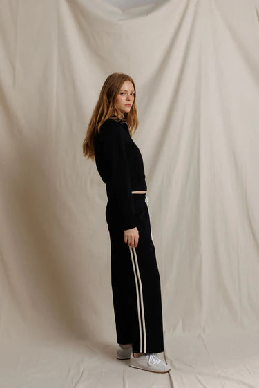 Person wearing a black outfit with white stripes on a beige background