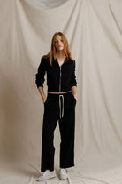 Person wearing a black tracksuit against a plain background