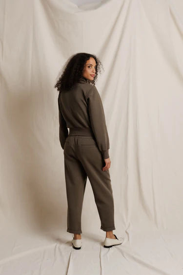 Woman wearing a brown outfit standing against a plain background