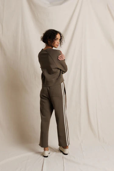 Woman wearing a green tracksuit with white stripes on a plain background