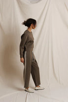Person wearing a brown tracksuit with white stripes on a plain background