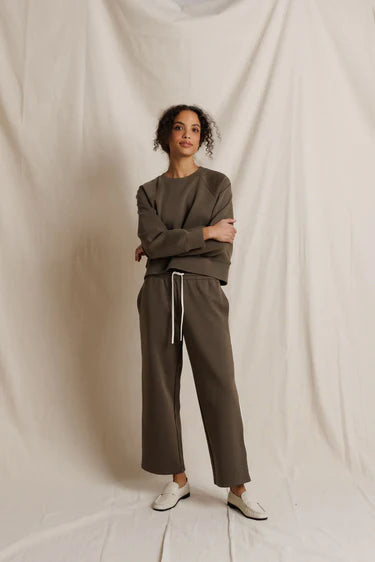 Woman wearing a brown outfit standing against a plain white background