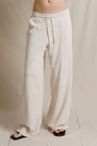 Beige wide-leg pants worn by a person on a neutral background