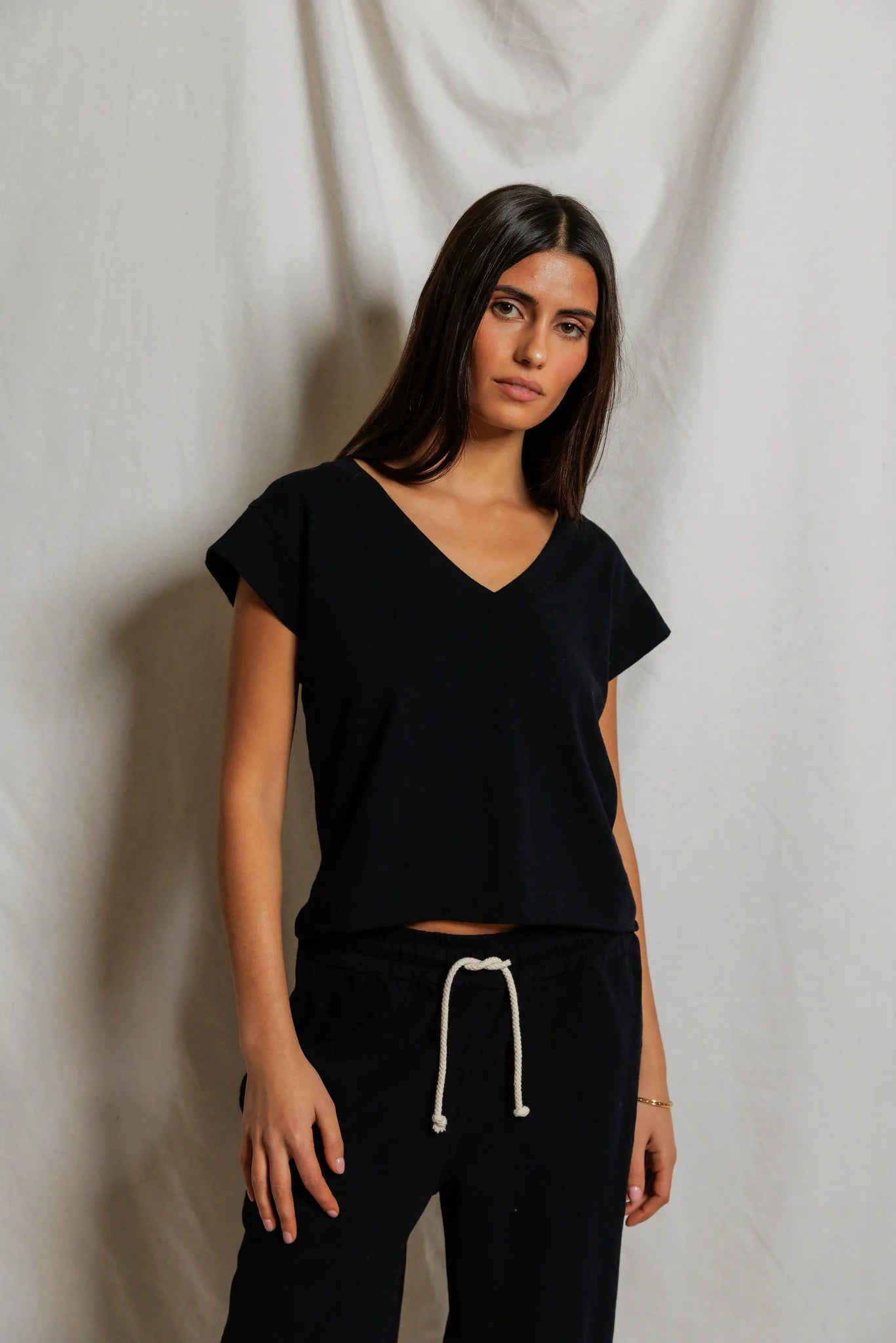 Woman wearing a black top and black pants against a plain background