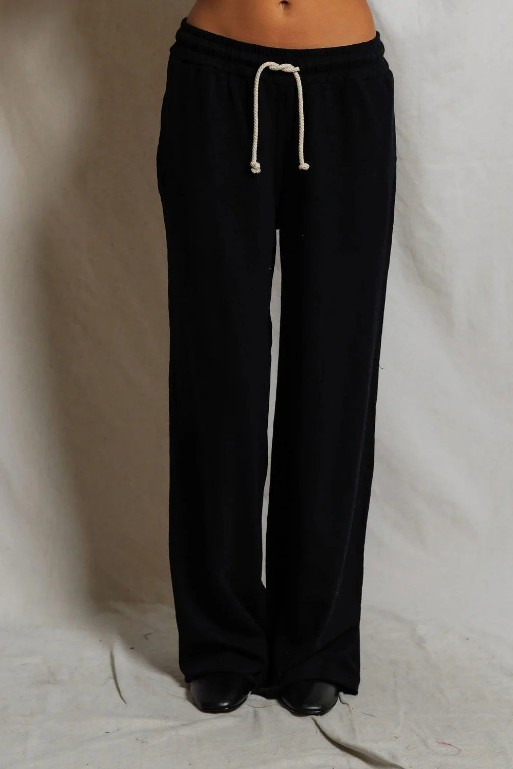 Black sweatpants with a white drawstring on a plain background