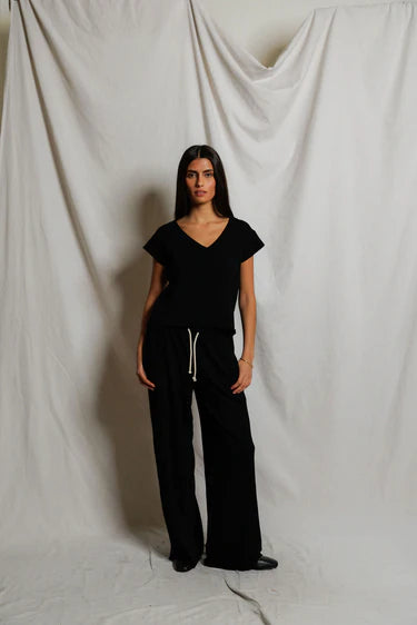 Person wearing a black outfit standing against a plain white background