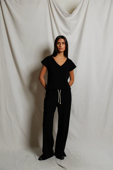 Person wearing a black outfit against a plain white background