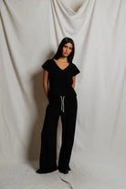 Woman wearing a black outfit against a white draped curtain background