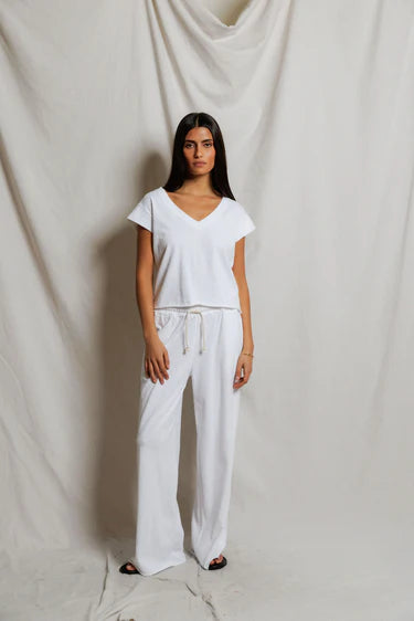 Woman wearing a white outfit standing against a plain background