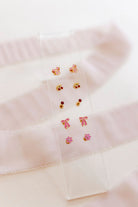 Set of earrings on a clear card with a soft pink background
