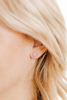 Close-up of a person wearing a small pink earring with a star design.