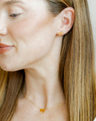Close-up of a person wearing gold stud earrings with a plain background