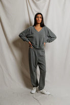 Woman wearing a gray lounge set against a plain background