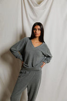 Woman wearing a gray lounge set against a plain background