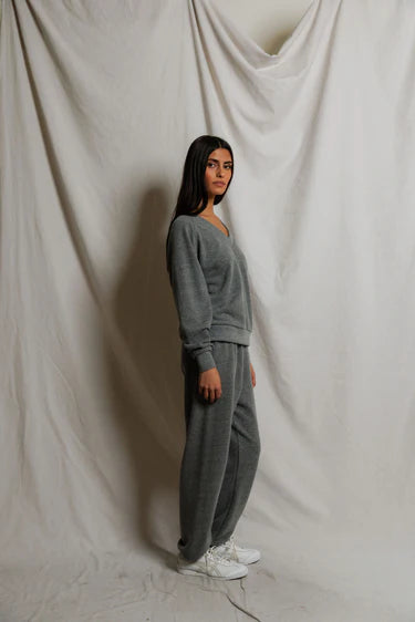 Person wearing a gray tracksuit standing against a plain white background