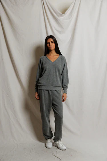 Person wearing a gray tracksuit against a plain background